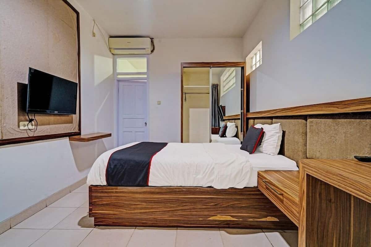 Un dormitorio con cama, televisor, espejo y equipo de aire acondicionado.