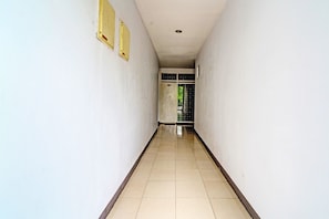 A narrow, tiled hallway with white walls and a door at the end. - Collection O 92277 Setra Priangan Guest House (Bandung)