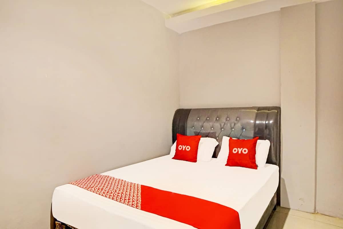 A hotel room with a bed, a headboard, and two pillows with the word "OYO" on them.