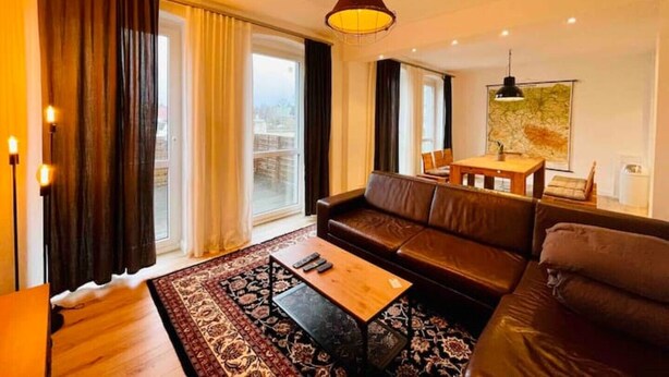 Een moderne woonkamer met een bank, een salontafel en een eethoek met een tafel en stoelen.