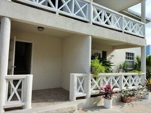 A two-story building with a balcony, potted plants, and a door.