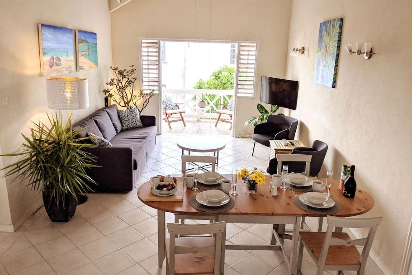 Un coin repas avec une table dressée pour quatre personnes, un canapé et un téléviseur en arrière-plan.