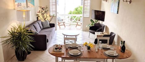 A dining area with a table set for four, a sofa, and a TV in the background.