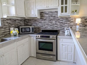 A kitchen with white cabinets, a microwave, a stove, and a toaster.