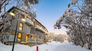 A multi-story building with balconies, a snow-covered driveway, and a clear sky. - Glacier Chalet - Luxury Mt Buller Ski Chalet • Fireplace •Sleeps 14 (Mount Buller)