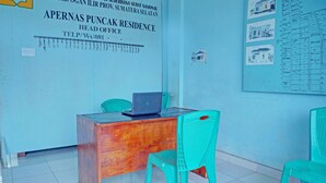 Une pièce avec un bureau en bois, un ordinateur portable et une chaise turquoise. Un mur est orné d’une affiche et d’un tableau d’affichage où sont accrochés des papiers et des dessins.