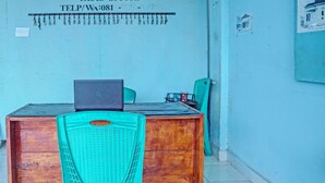 Une pièce avec un bureau en bois, une chaise en plastique turquoise et un ordinateur portable.