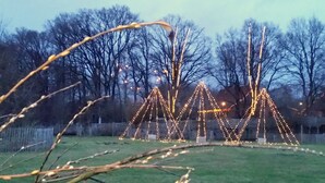 A large, open field with a series of illuminated structures resembling tents or pyramids. - Luxury holiday home with every comfort - sauna, bathtub with whirlpool function (Nordhorn)