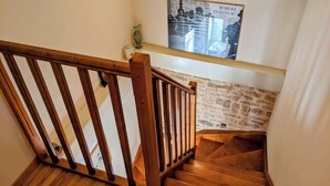 A wooden staircase with a stone wall and a poster of Robert Doisneau.