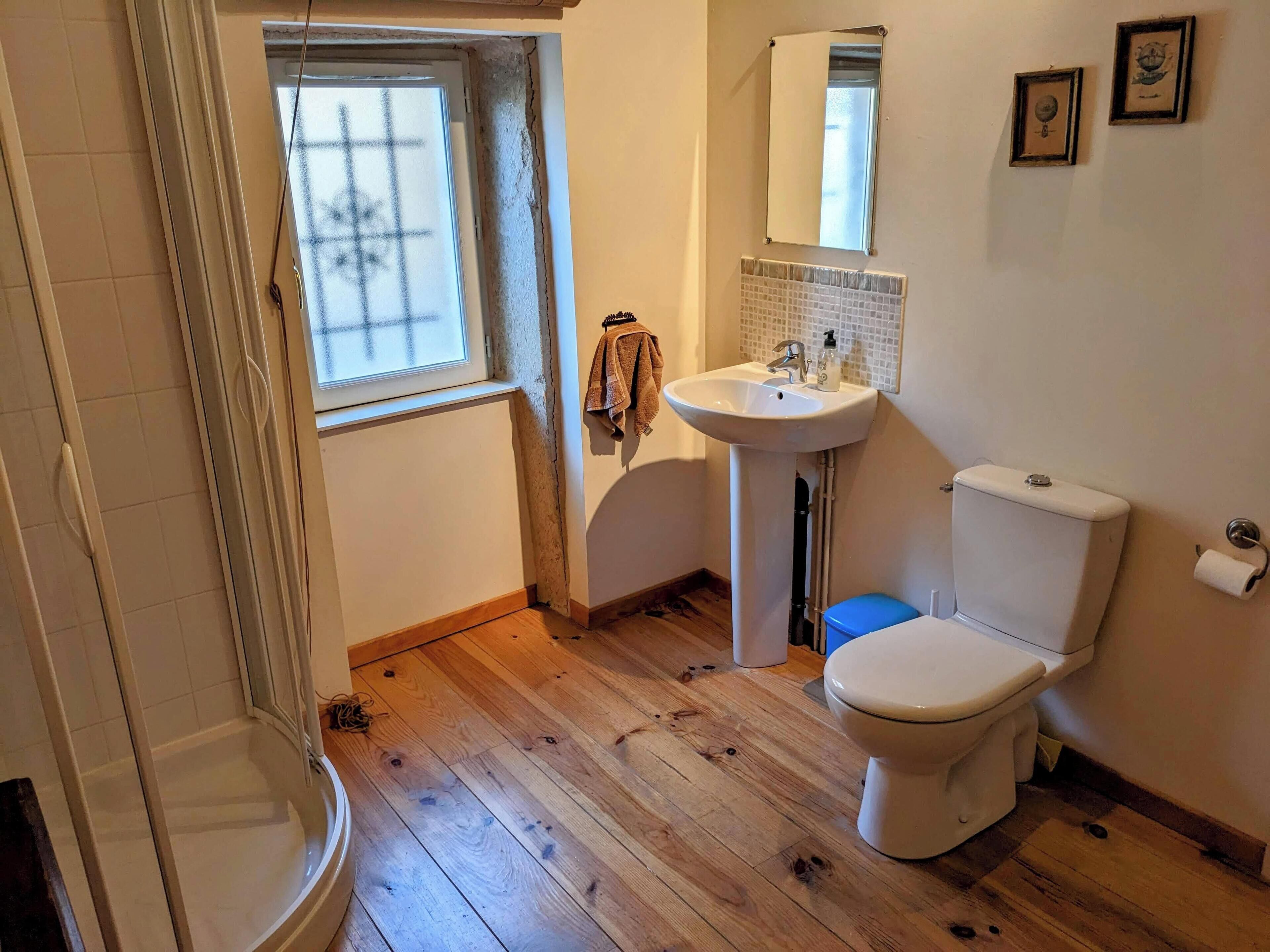 Une salle de bain avec des toilettes, un lavabo et une fenêtre.