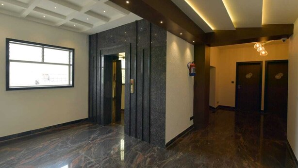Un moderno vestíbulo de hotel con piso de mármol, un ventanal grande y una pared de acento oscura.