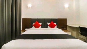 Una habitación de hotel con una cama grande, dos mesitas de noche, una silla y un escritorio.