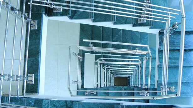Un escalier en colimaçon avec des rampes en métal et un mur recouvert de miroirs.