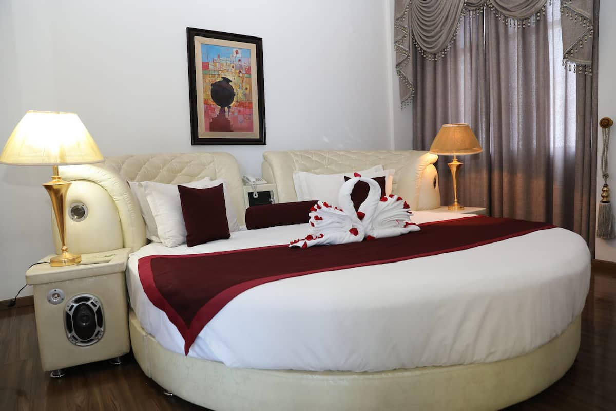 A well-appointed hotel room with a large bed, two bedside lamps, a telephone, and a framed picture on the wall.