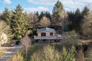Eine Hütte mit Terrasse, umgeben von Bäumen.