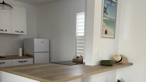 Eine Küche mit Holzarbeitsplatte, weißen Schränken, einem Kühlschrank und einem Korbwäschesammler auf dem Boden.