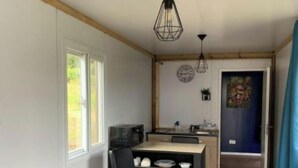 Cozinha compacta com área de refeições, um sofá e porta que dá para outro quarto.