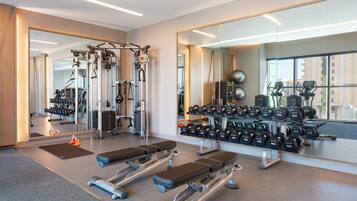 Un gimnasio moderno con equipo cardiovascular, bancos de pesas y una barra de mancuernas.