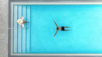 Vista aérea de una piscina rectangular con agua azul cristalina, bordes azulejados y una escalera metálica en un lateral.