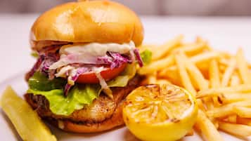 Una hamburguesa con papas fritas y un gajo de limón en un plato.