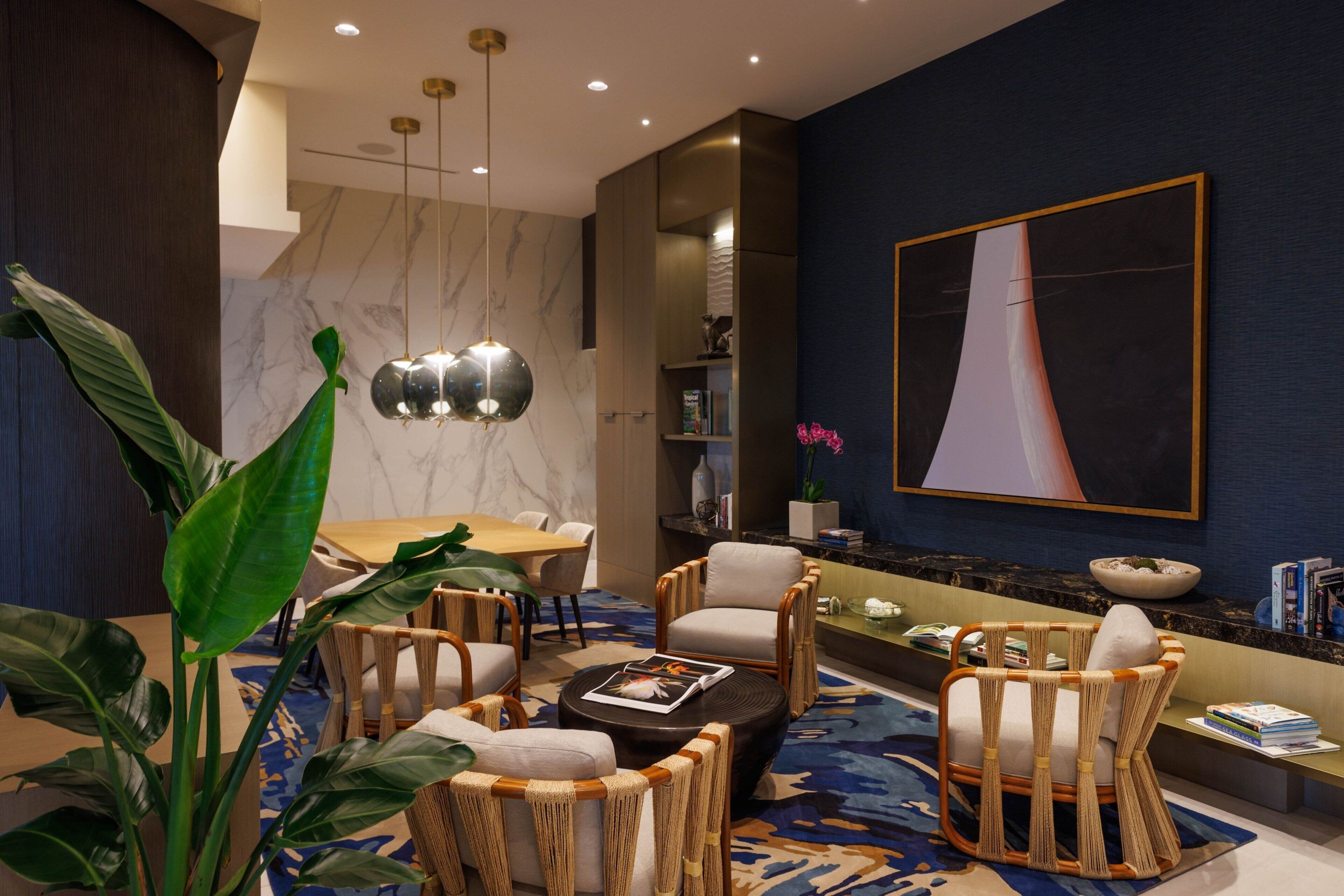 Una sala de estar moderna con una pared de mármol, un cuadro abstracto grande y una zona de comedor con una mesa y sillas de madera.