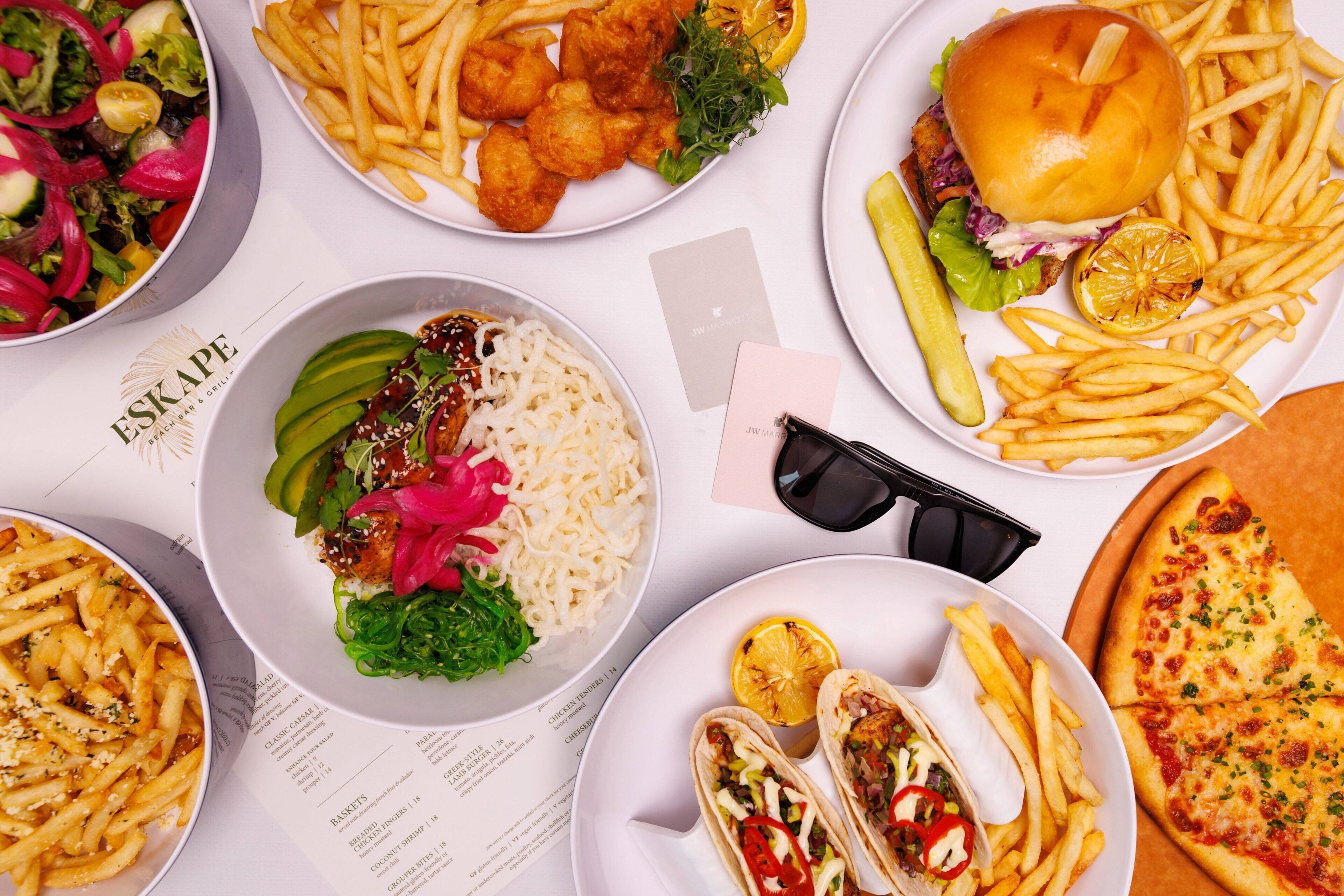 Variedad de platillos, incluyendo una hamburguesa, papas fritas, tacos y una pizza.
