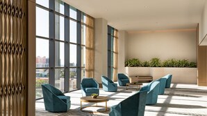 A spacious lobby with large windows, modern seating, and a view of the city.