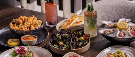 Diversos platos que incluyen mariscos, ensaladas y pan, dispuestos sobre una mesa de madera.
