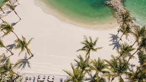 An aerial view of a beach with white sand, clear turquoise water, and palm trees. - JW Marriott Clearwater Beach Resort & Spa (Clearwater Beach)