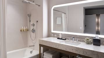 Un baño moderno con bañera, ducha, tocador y un espejo grande.