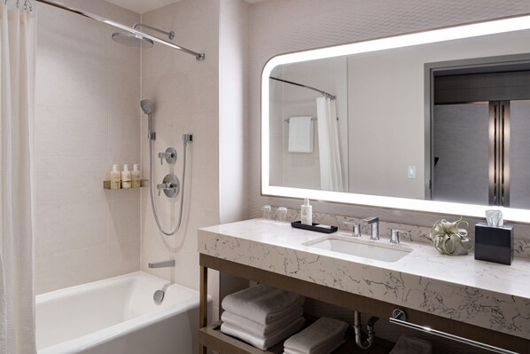 Un baño moderno con bañera, ducha, tocador y un espejo grande.