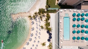 An aerial view of a hotel with a beachside pool, sun loungers, and palm trees. - JW Marriott Clearwater Beach Resort & Spa (Clearwater Beach)