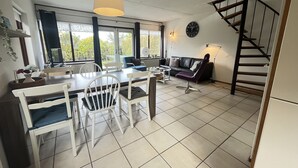 Ein geräumiger Wohnbereich mit Esstisch, Stühlen, einer Couch und einer Treppe.