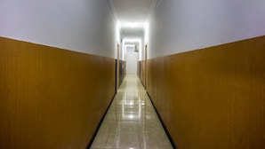 A long, narrow hallway with wooden paneling on the walls and a shiny tiled floor. - Hotel O Wisma Permata Makassar (Makassar)