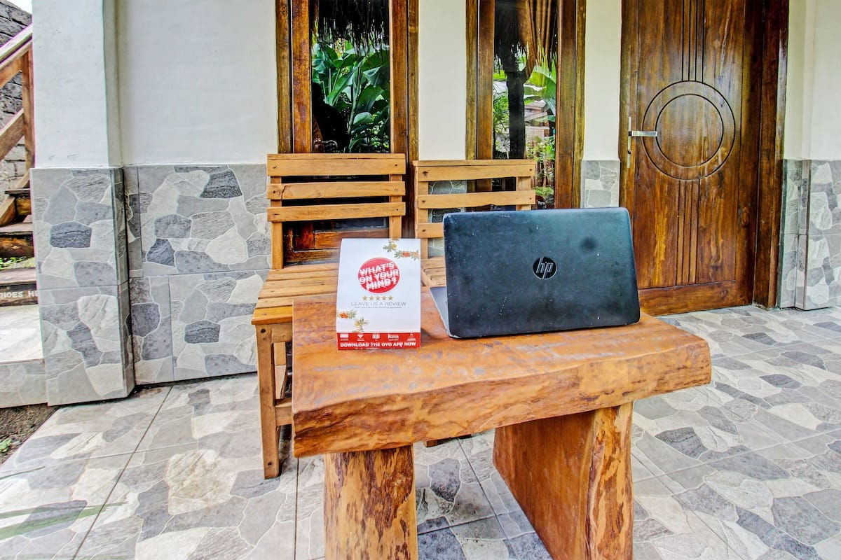 Une table en bois avec un ordinateur portable et une pancarte devant un bâtiment dont la façade est ornée de pierres et de bois.