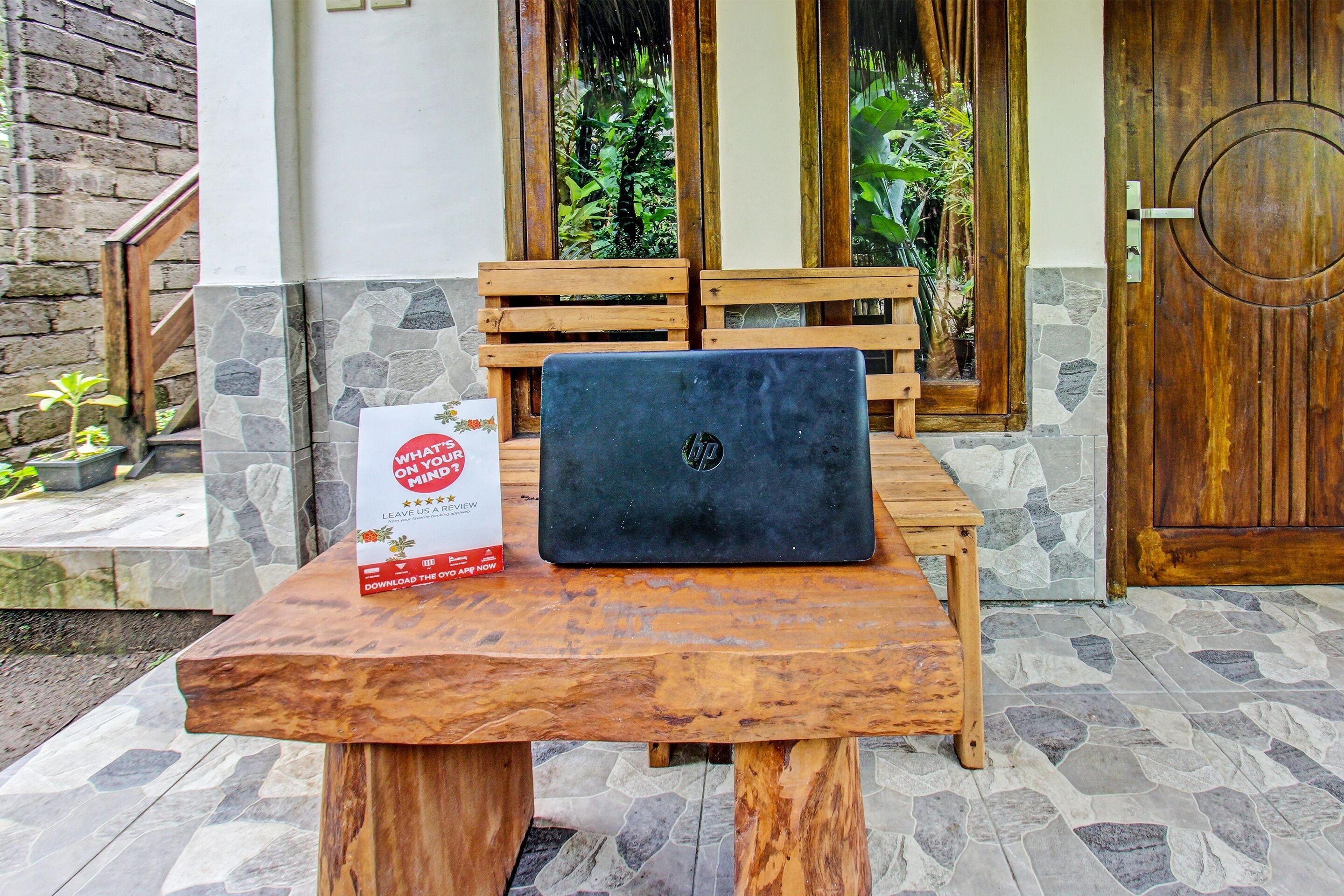 Een houten tafel met een laptop en een bordje erop.