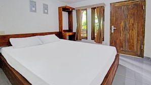 Ein ordentlich bezogenes Bett in einem Zimmer mit Holz-Kopfteil, Holzschrank und kleinem Tisch mit Spiegel.