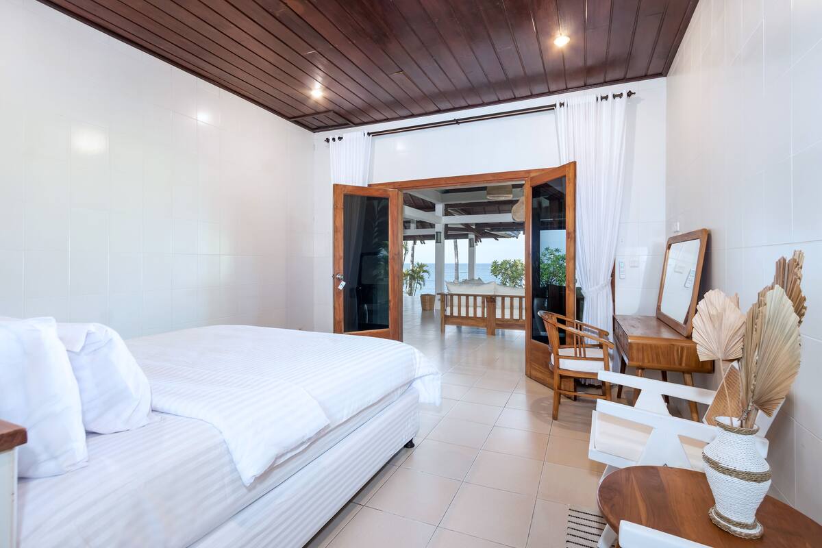 A hotel room with a bed, wooden furniture, and a view of the outdoors.