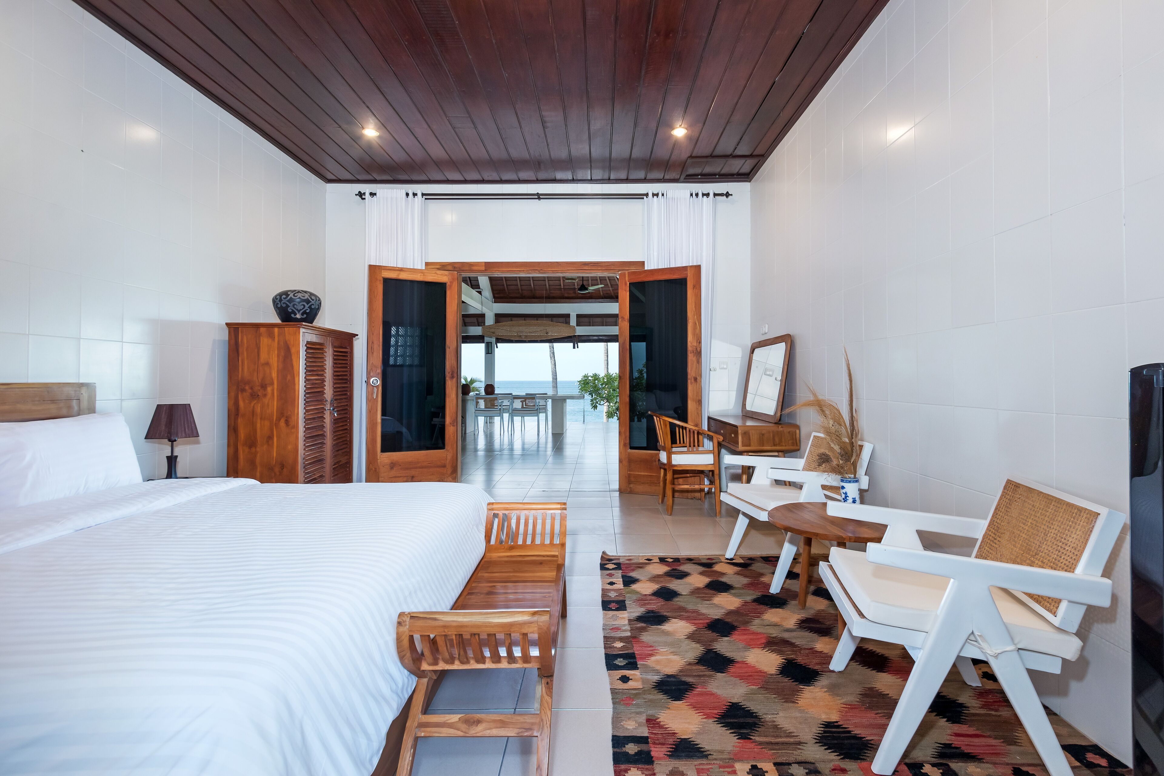 Habitación de hotel con una cama grande, muebles de madera, una zona de comedor y vistas al exterior.