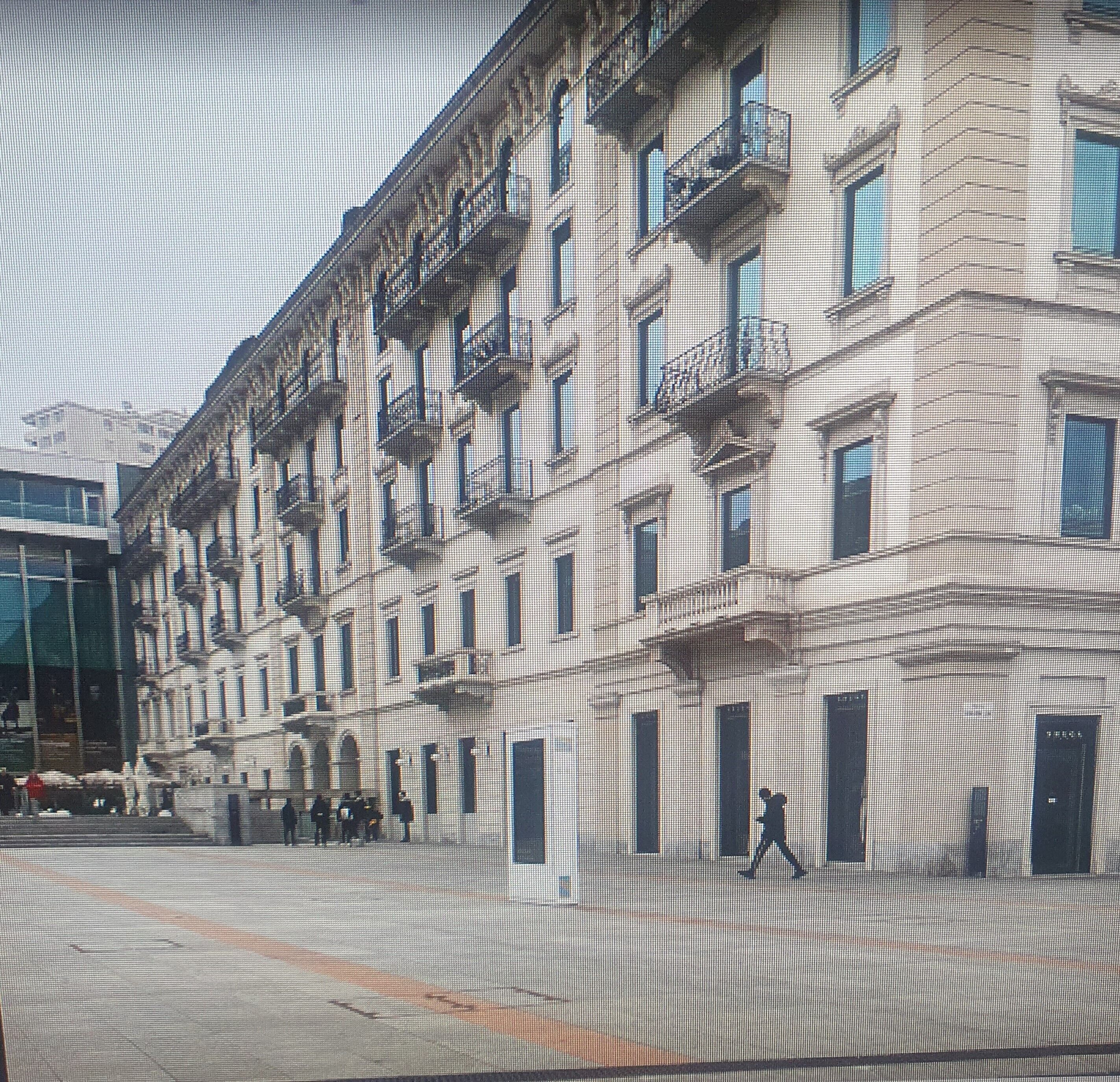 A multi-story building with balconies and a ground-level entrance.
