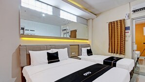 A hotel room with two beds, a large mirror, and a window. - Capital O 92295 Double Tree (Purwokerto)