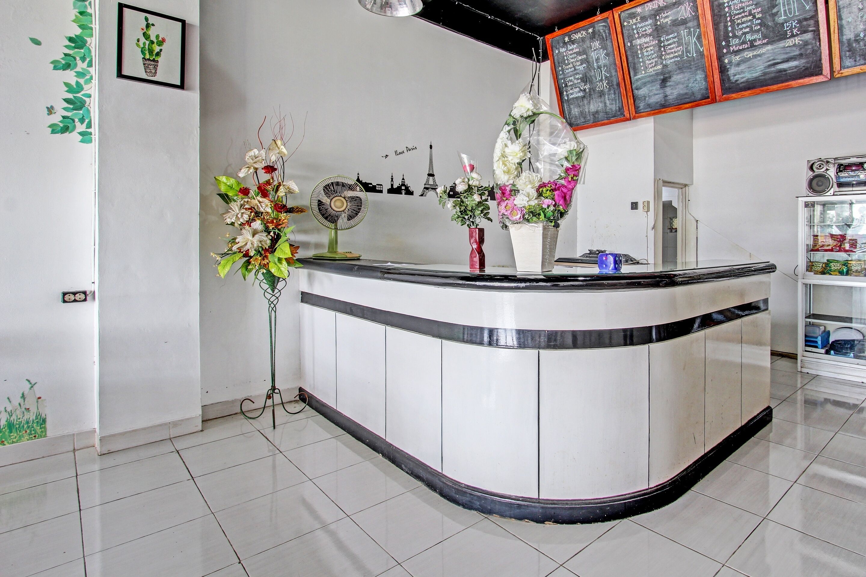 A reception area with a curved counter, a fan, and floral arrangements.