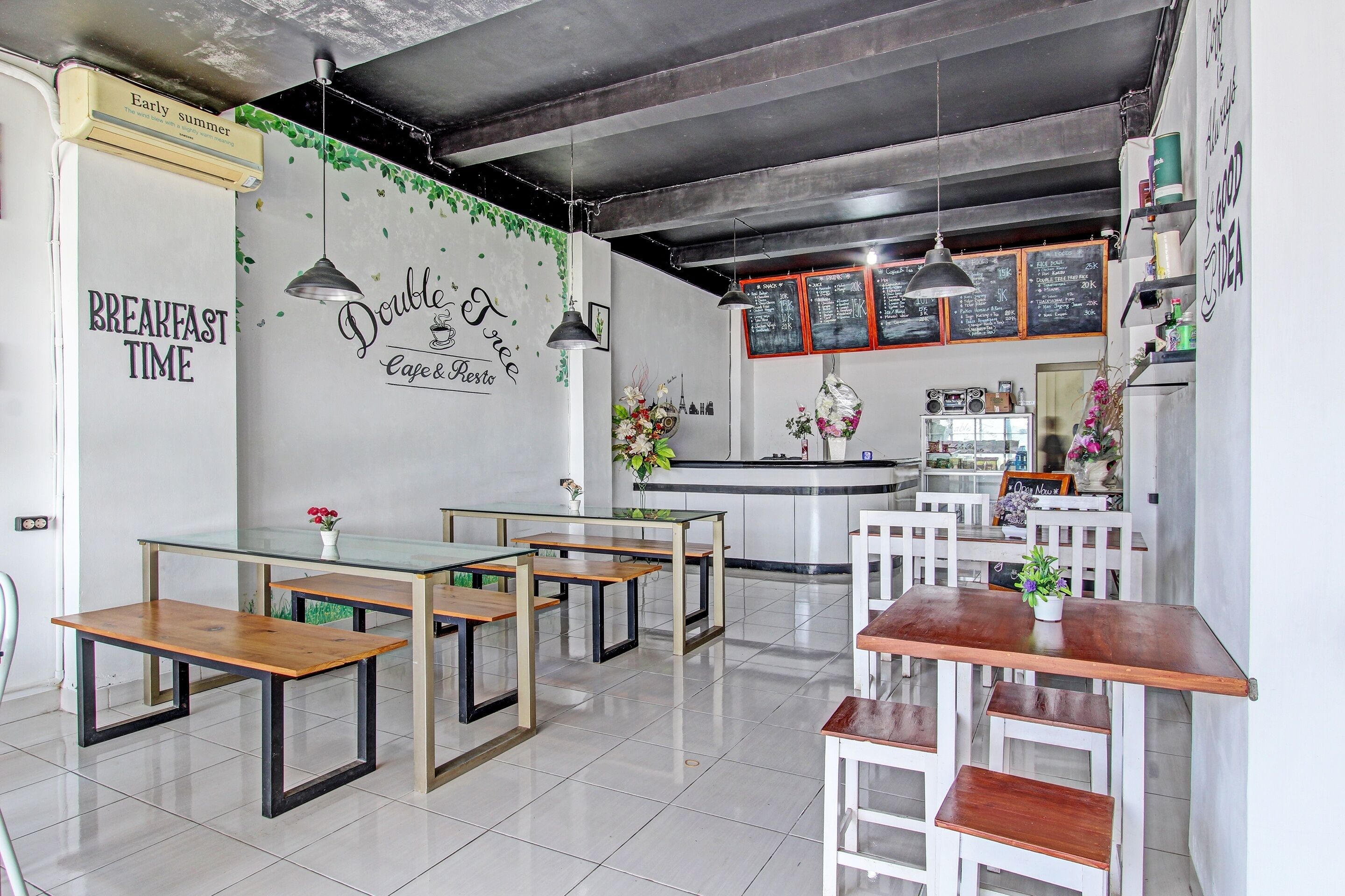 A cafe with wooden tables and chairs, a chalkboard menu, and a wall with 'Breakfast Time' and 'Double Espresso' written on it.