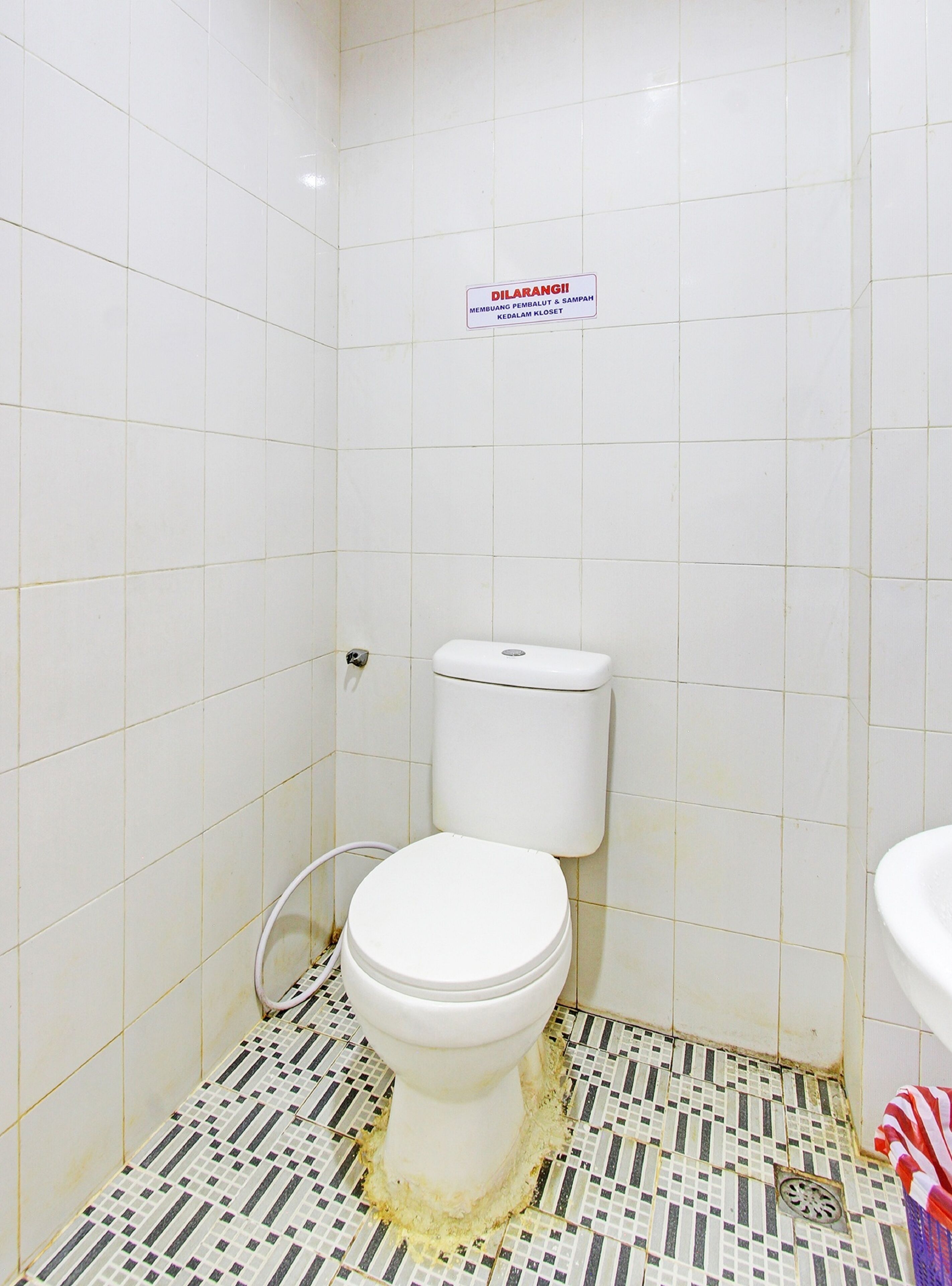 A small bathroom with a toilet, a sign above the toilet, and a tiled floor.