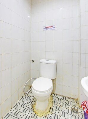 A small bathroom with a toilet, a sign above the toilet, and a tiled floor. - Capital O 92295 Double Tree (Purwokerto)