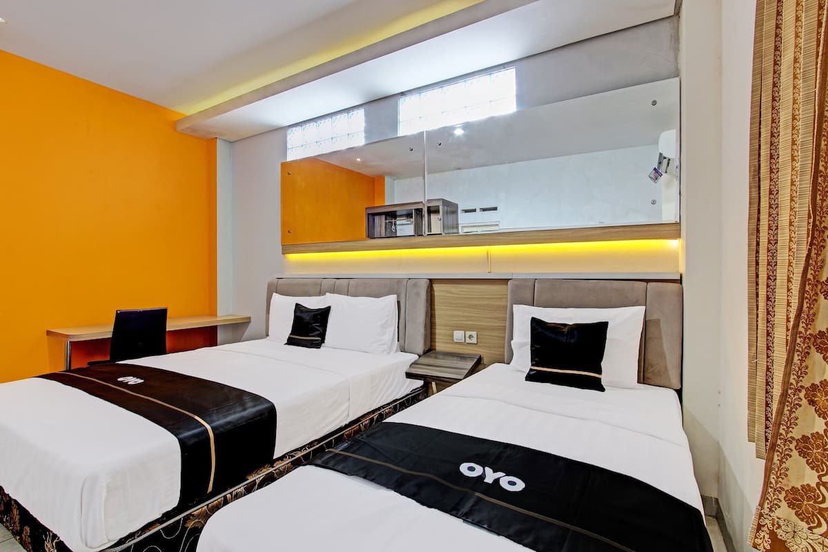 A hotel room with two beds, a desk, and a large mirror.