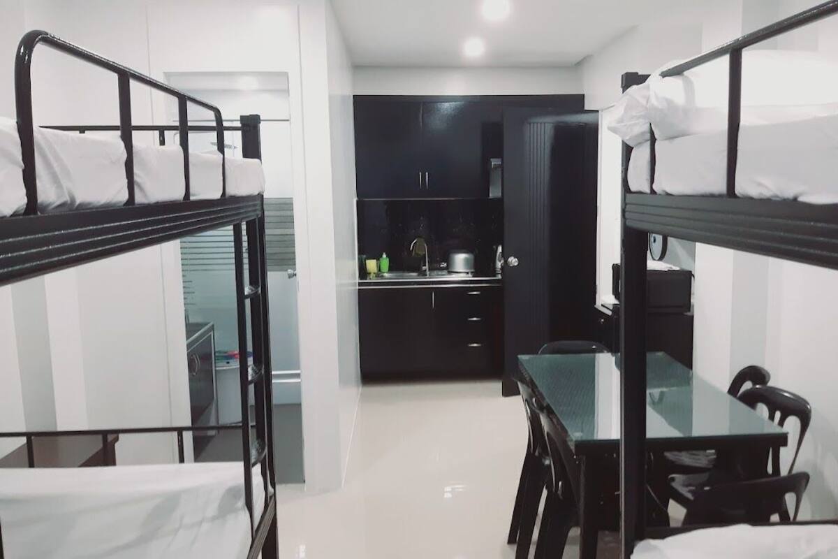 Une chambre de dortoir avec des lits superposés, une petite kitchenette et une table à manger avec des chaises.