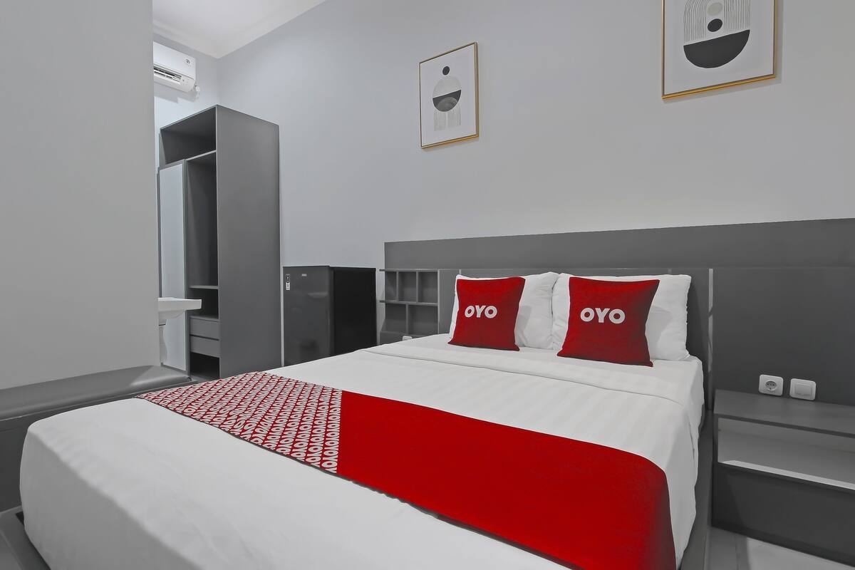 Quarto de hotel com cama, guarda-roupa, mesa de cabeceira e ar condicionado fixado na parede.