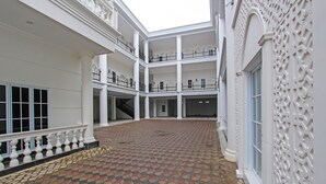A spacious courtyard with a patterned floor, white columns, and balconies. - Capital O 92105 A'shanti Inn (Cilacap)