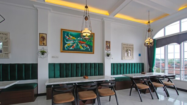 A restaurant with green upholstered booths, a marble-top table, and hanging pendant lights. - Capital O 92105 A'shanti Inn (Cilacap)